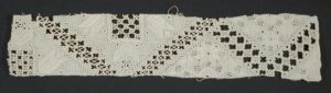 A length of cutwork lace in white on a black background